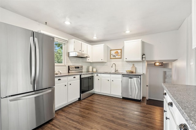 7565 Newland St, Arvada, CO 80003 - kitchen with stainless steel appliances, under cabinet range hood, decorative backsplash, white cabinetry, and recessed lighting