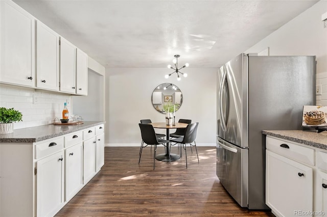 7565 Newland St, Arvada, CO 80003 - kitchen with freestanding refrigerator, dark wood-type flooring, white cabinetry, tasteful backsplash, and a chandelier