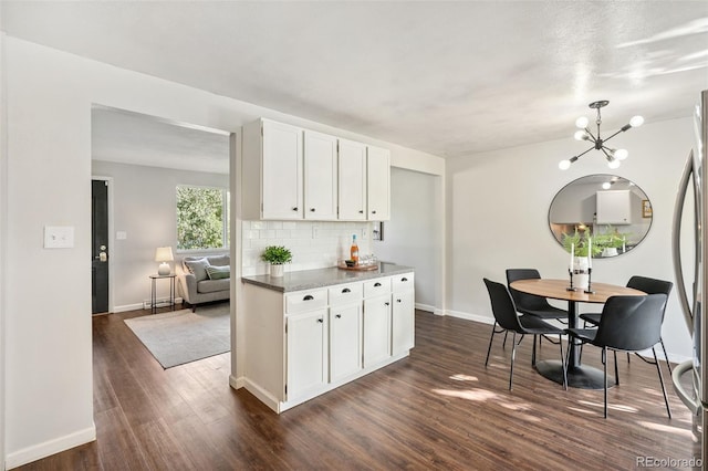 7565 Newland St, Arvada, CO 80003 - kitchen featuring white cabinetry, tasteful backsplash, dark wood finished floors, and a chandelier