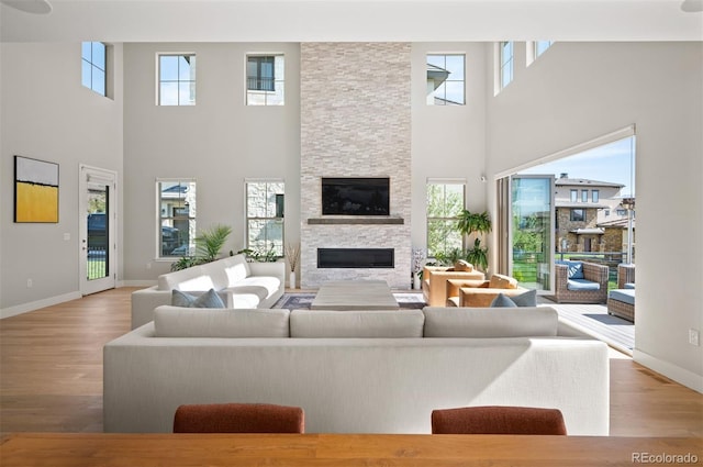 2136 S Juniper St, Lakewood, CO 80228 - living area featuring healthy amount of natural light, a towering ceiling, wood finished floors, baseboards, and a fireplace