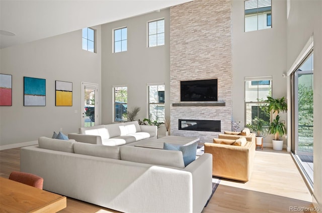 2136 S Juniper St, Lakewood, CO 80228 - living area with a high ceiling, a stone fireplace, light wood-type flooring, and baseboards