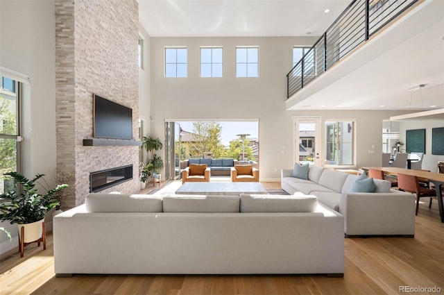 2136 S Juniper St, Lakewood, CO 80228 - living room featuring a towering ceiling, wood finished floors, healthy amount of natural light, and a stone fireplace