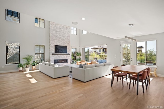 2136 S Juniper St, Lakewood, CO 80228 - living room with a stone fireplace, healthy amount of natural light, baseboards, light wood finished floors, and a towering ceiling