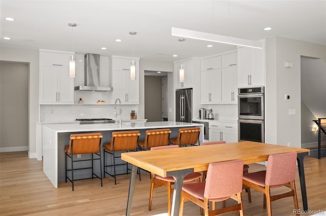 2136 S Juniper St, Lakewood, CO 80228 - kitchen featuring wall chimney range hood, stainless steel appliances, a kitchen island with sink, backsplash, and recessed lighting