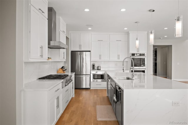 2136 S Juniper St, Lakewood, CO 80228 - kitchen with stainless steel appliances, a sink, wall chimney range hood, white cabinets, and pendant lighting