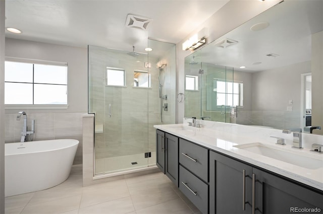 2136 S Juniper St, Lakewood, CO 80228 - bathroom with a shower stall, tile walls, double vanity, tile patterned flooring, and a freestanding tub