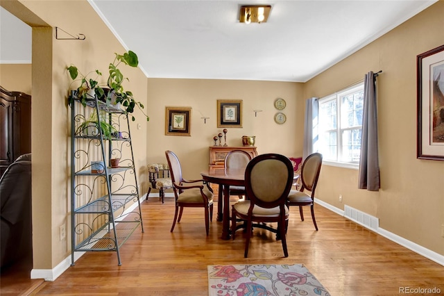 dining area with ornamental molding, wood finished floors, visible vents, and baseboards