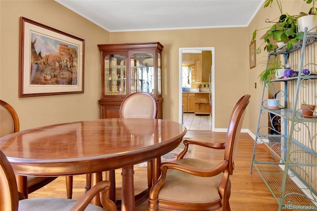 dining space with baseboards, light wood-type flooring, and crown molding