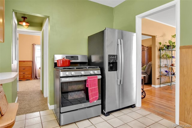 kitchen featuring ornamental molding, appliances with stainless steel finishes, and light tile patterned flooring