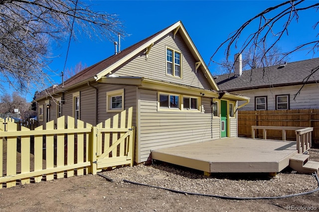 rear view of house featuring a deck and fence