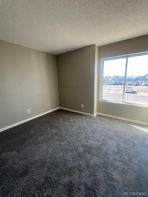 carpeted empty room featuring a textured ceiling