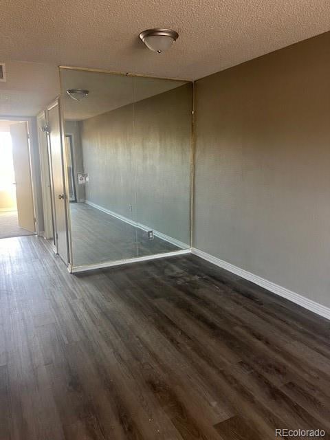 unfurnished room with dark wood-type flooring and a textured ceiling