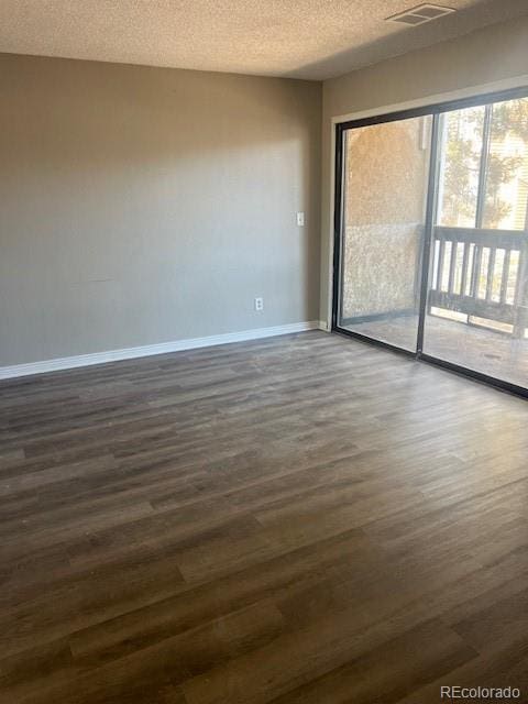 unfurnished room featuring dark wood-type flooring and a textured ceiling