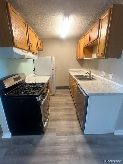 kitchen with hardwood / wood-style floors, appliances with stainless steel finishes, sink, and a textured ceiling