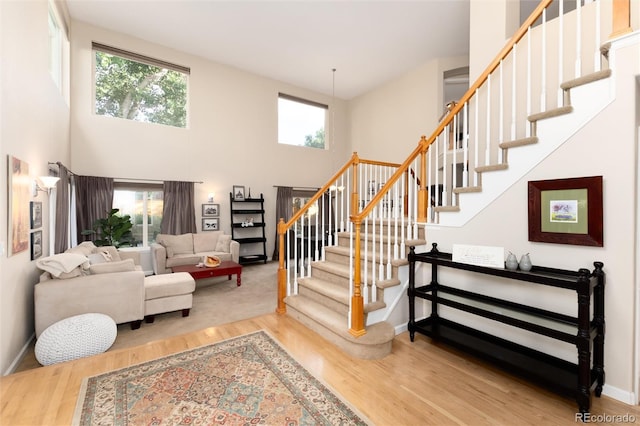 stairs featuring baseboards, a towering ceiling, and wood finished floors