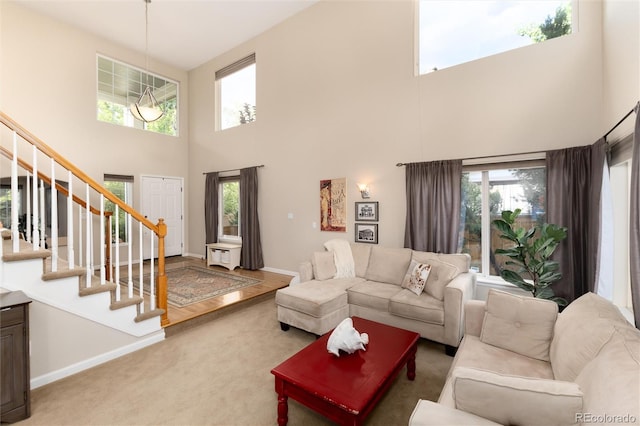 living area featuring carpet floors, baseboards, stairs, and a towering ceiling