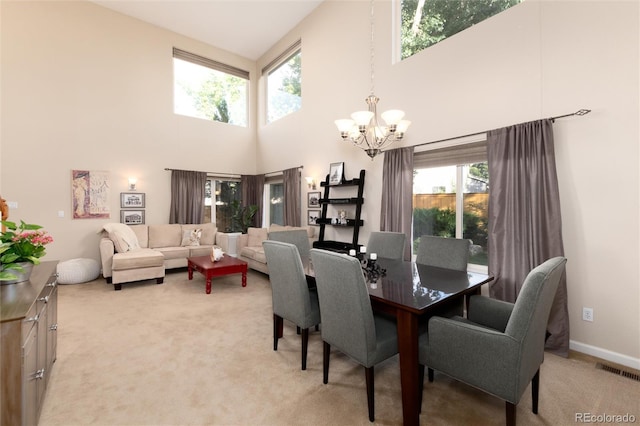dining room with light colored carpet, visible vents, an inviting chandelier, a high ceiling, and a wealth of natural light