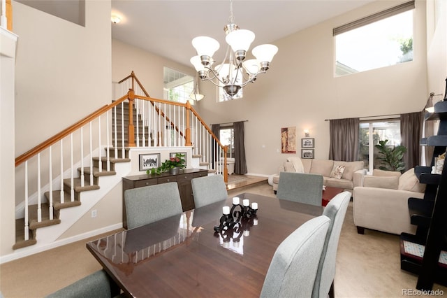 dining room featuring an inviting chandelier, a wealth of natural light, stairs, and a towering ceiling