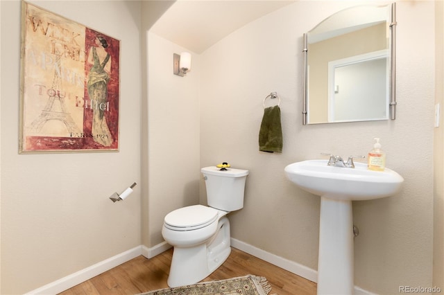 bathroom with baseboards, toilet, and wood finished floors