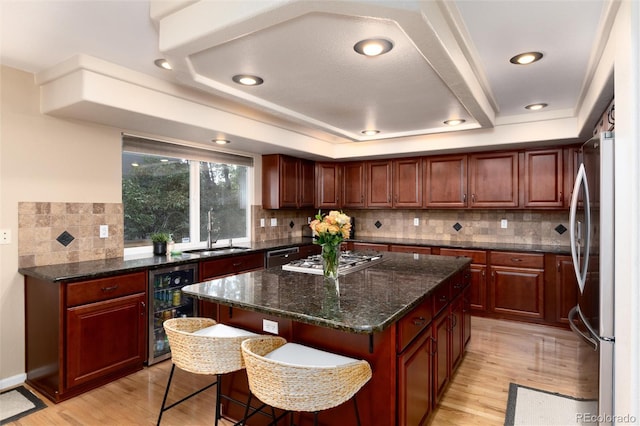 kitchen featuring gas cooktop, a sink, freestanding refrigerator, wine cooler, and a kitchen island