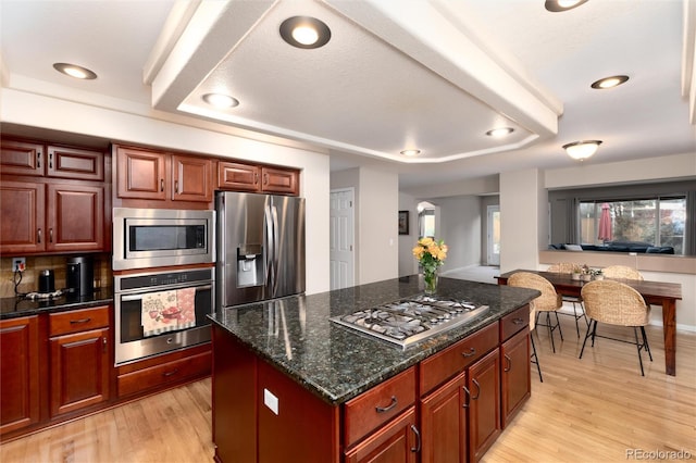 kitchen featuring recessed lighting, dark stone countertops, stainless steel appliances, and light wood finished floors