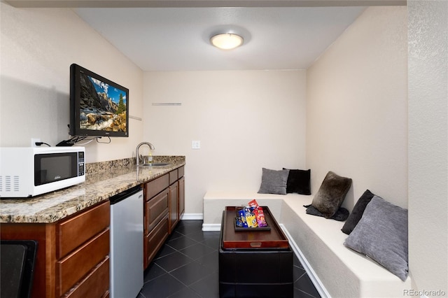 bar featuring a sink, white microwave, dark tile patterned flooring, refrigerator, and dishwashing machine