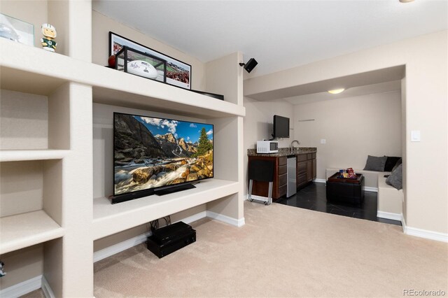 home theater room featuring baseboards and dark carpet