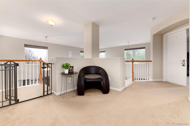 living area featuring carpet flooring, baseboards, and an upstairs landing