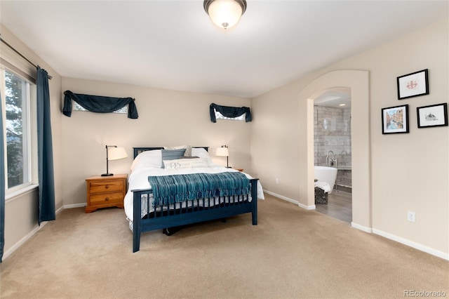 bedroom with carpet floors, baseboards, and arched walkways