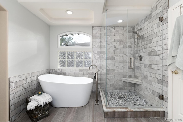 full bath with a freestanding tub, wood finished floors, tile walls, recessed lighting, and a stall shower