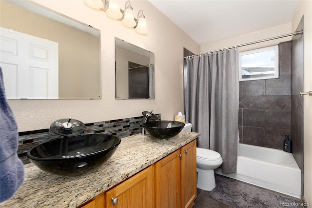 bathroom featuring a sink, toilet, double vanity, shower / tub combo, and backsplash