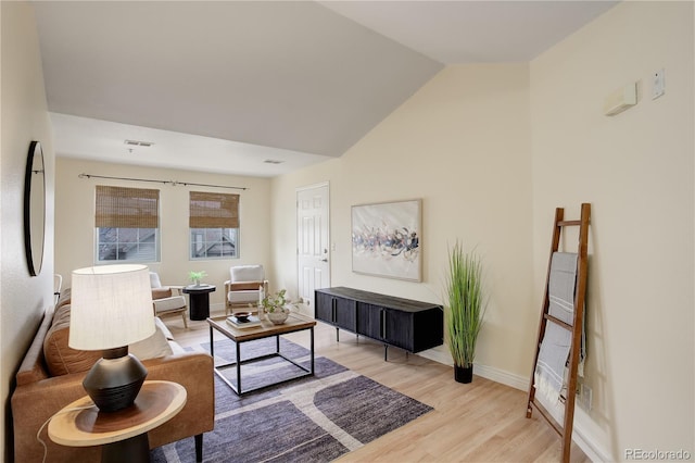 living area with visible vents, baseboards, light wood finished floors, and lofted ceiling