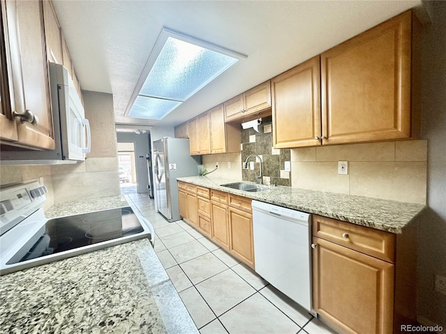 kitchen featuring decorative backsplash, light tile patterned flooring, white appliances, light stone countertops, and sink