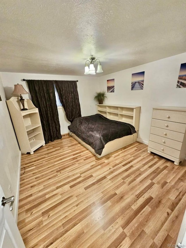 bedroom with light hardwood / wood-style floors and a textured ceiling