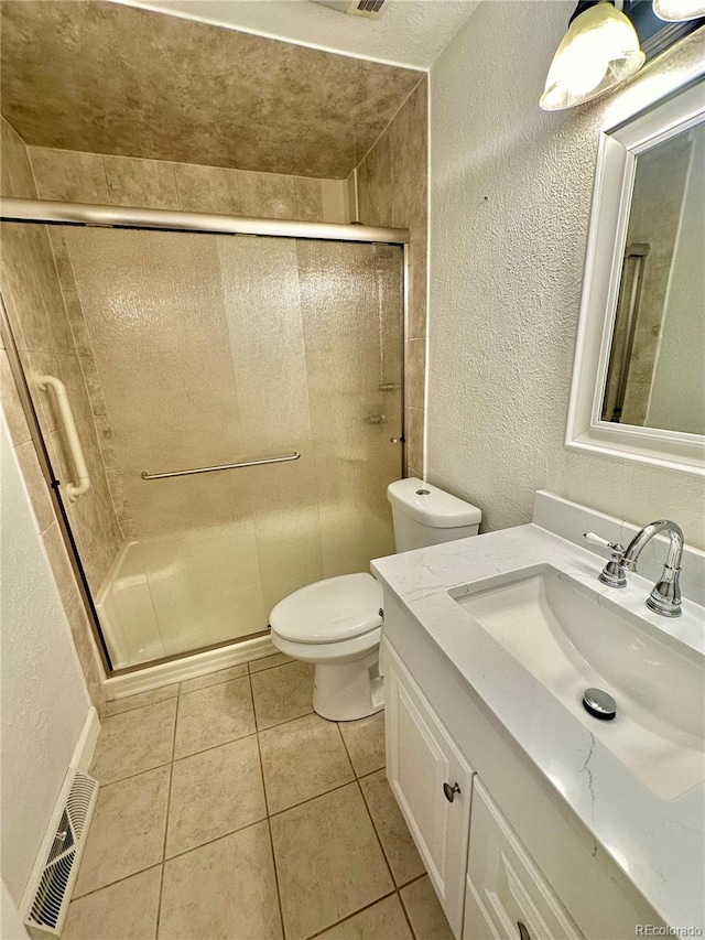 bathroom with tile patterned flooring, vanity, toilet, and a shower with shower door