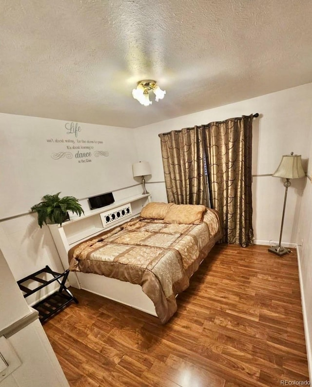 bedroom with a textured ceiling and wood-type flooring