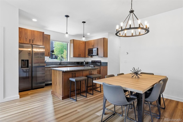 dining area featuring sink, an inviting chandelier, and light wood-type flooring