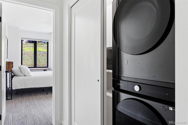 washroom featuring stacked washer / dryer and carpet