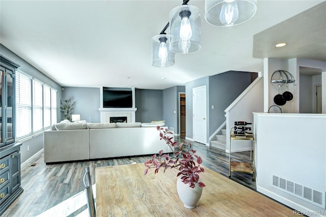 living area featuring light wood finished floors, baseboards, visible vents, stairway, and a fireplace