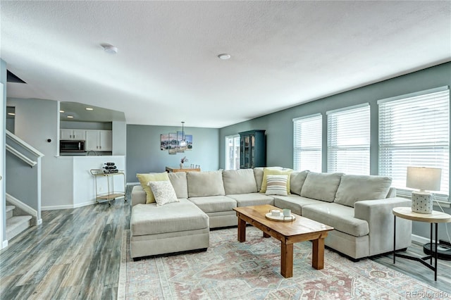 living room with light wood-type flooring, stairway, baseboards, and a textured ceiling