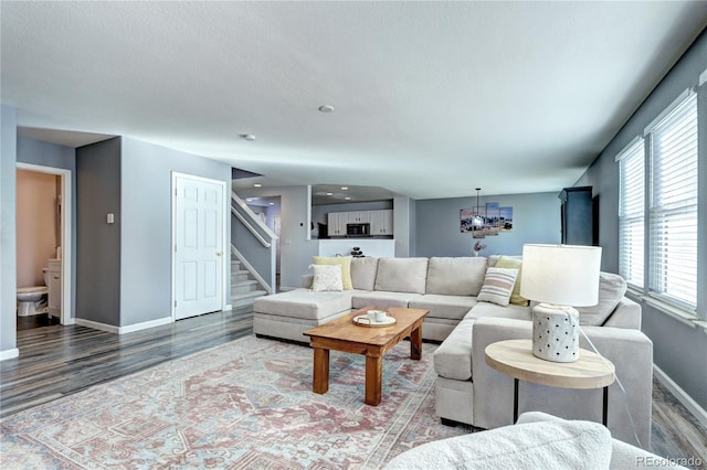 living room with a notable chandelier, stairway, a textured ceiling, wood finished floors, and baseboards