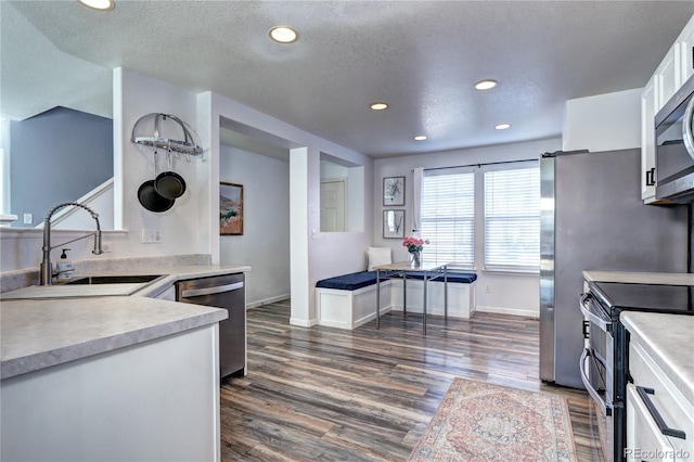 kitchen with white cabinets, stainless steel appliances, a sink, and light countertops