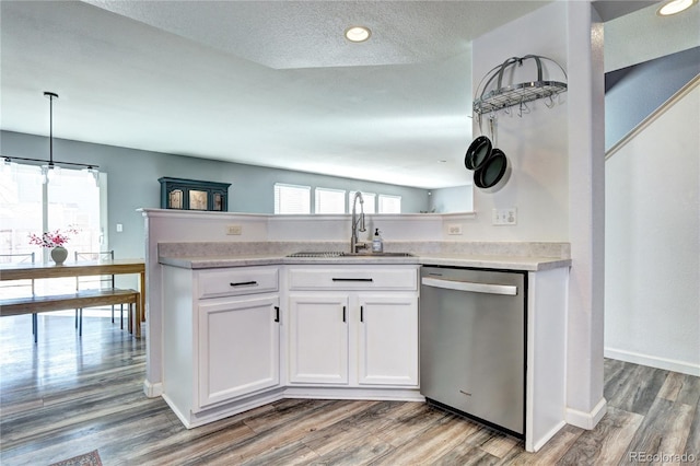 kitchen with wood finished floors, a sink, white cabinets, light countertops, and dishwasher