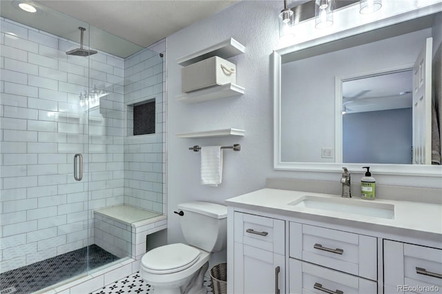 bathroom featuring toilet, a textured wall, a shower stall, and vanity