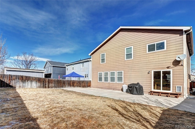 rear view of property featuring a yard, fence, and a patio