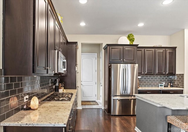 7790 S Queensburg Way, Aurora, CO 80016 - kitchen featuring appliances with stainless steel finishes, dark brown cabinetry, dark wood finished floors, backsplash, and light stone counters