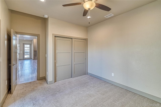 unfurnished bedroom with ceiling fan, light colored carpet, and a closet