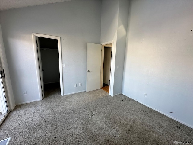 unfurnished bedroom with a walk in closet and light carpet