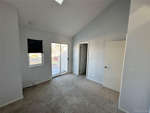 empty room featuring light carpet, a textured ceiling, and vaulted ceiling