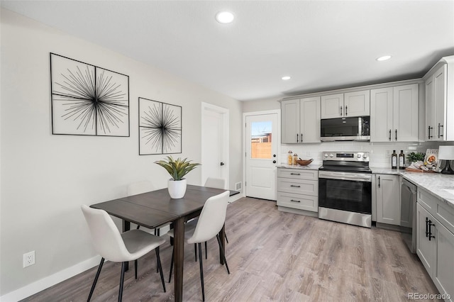 4903 W 11th Ave, Denver, CO 80204 - kitchen with stainless steel appliances, gray cabinetry, tasteful backsplash, light wood-type flooring, and recessed lighting